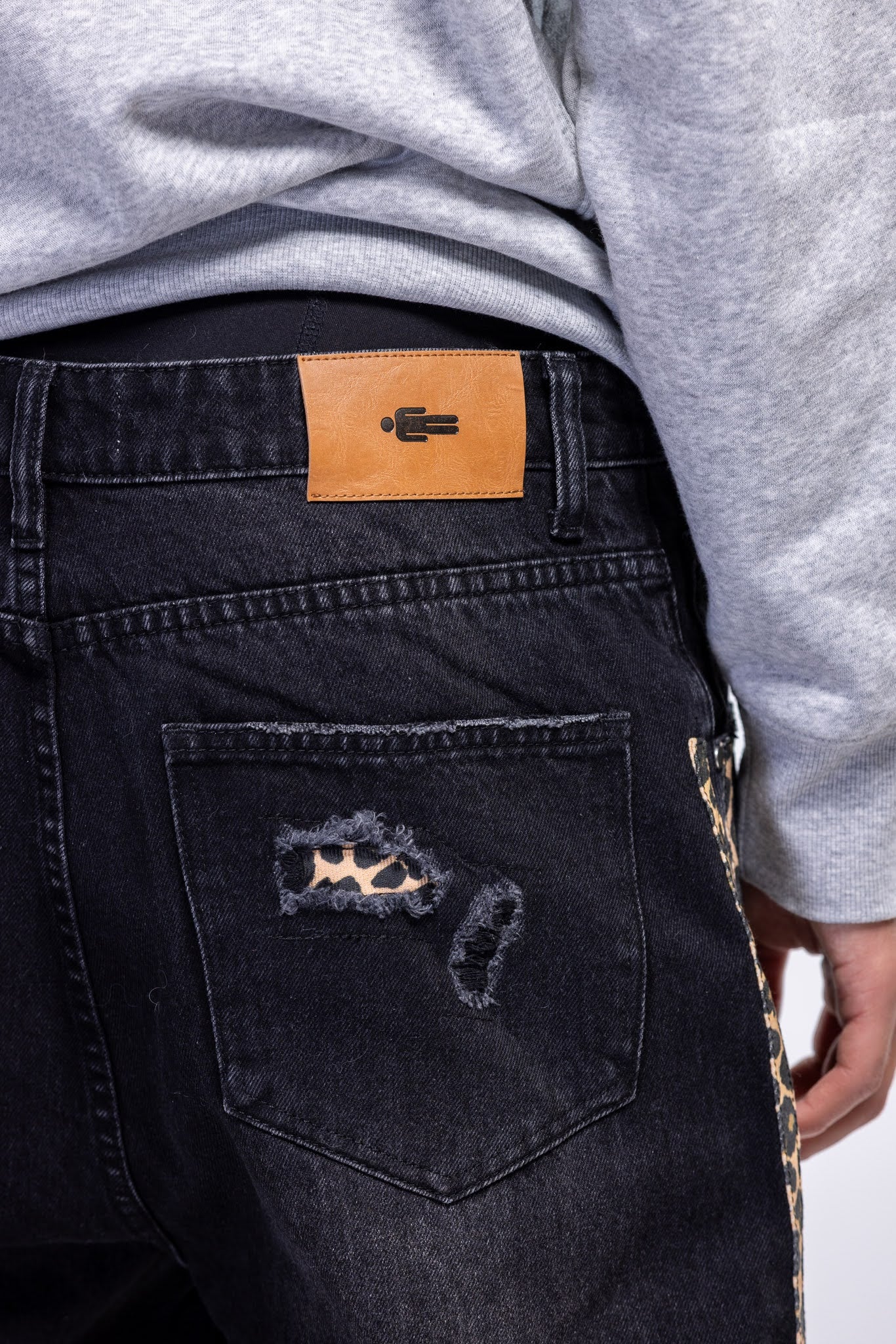Black distressed jeans with a brand patch on the back pocket