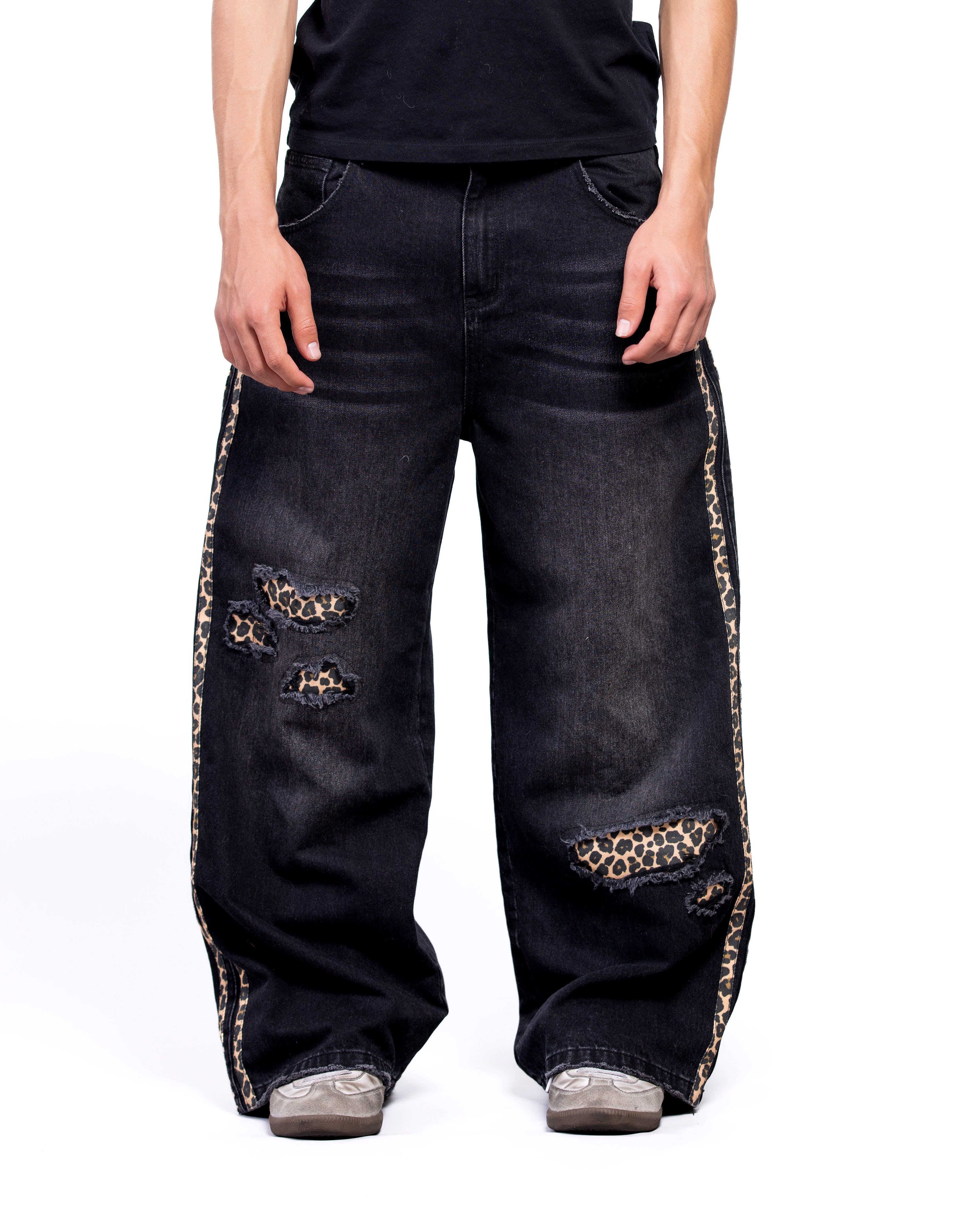 Black jeans with leopard print patches worn by a person on a white background