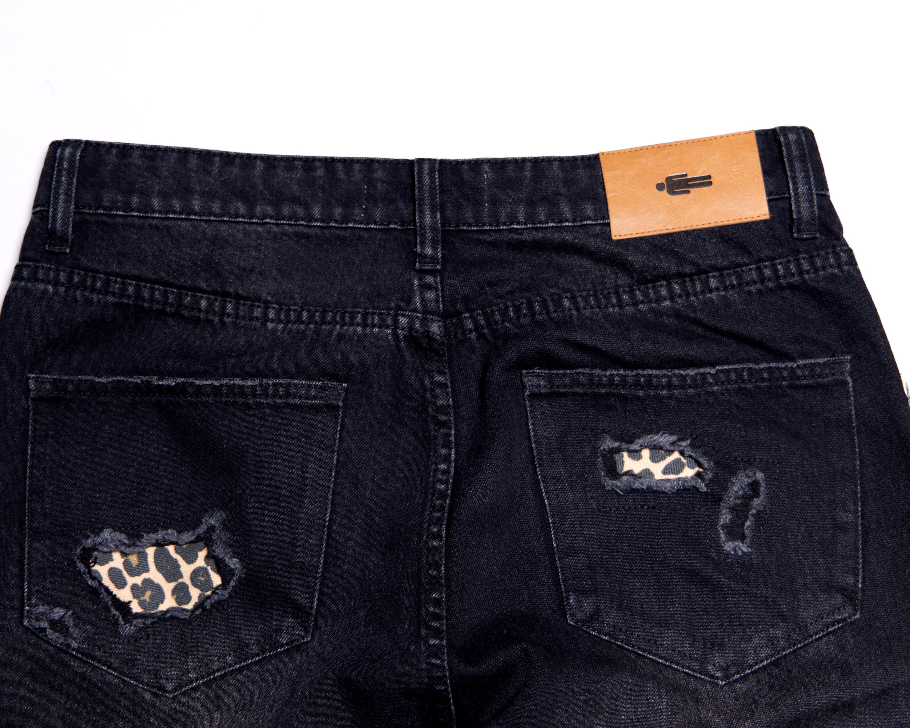 Black distressed jeans with leopard print patches on a white background
