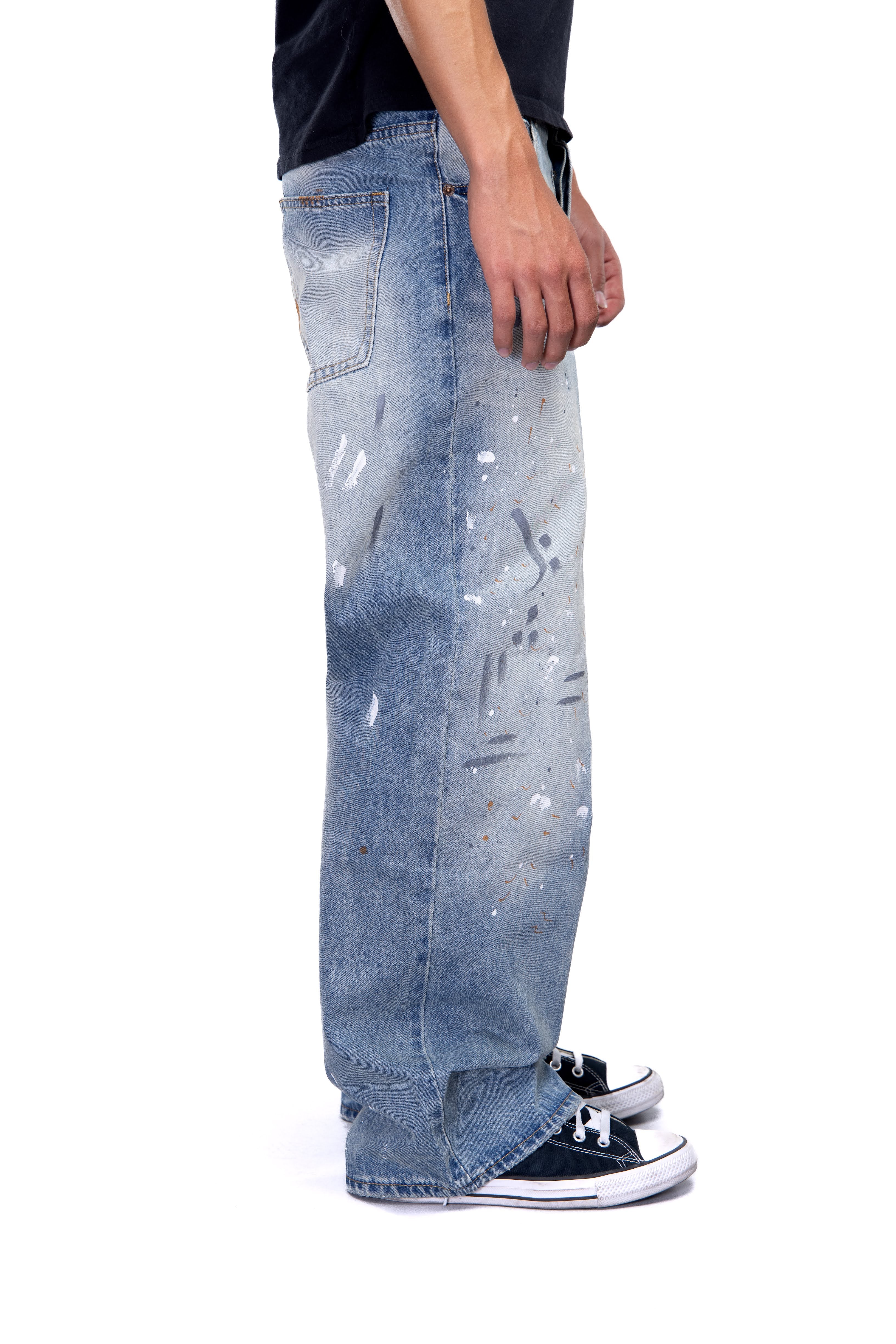 Blue jeans with white paint splashes worn by a person on a white background