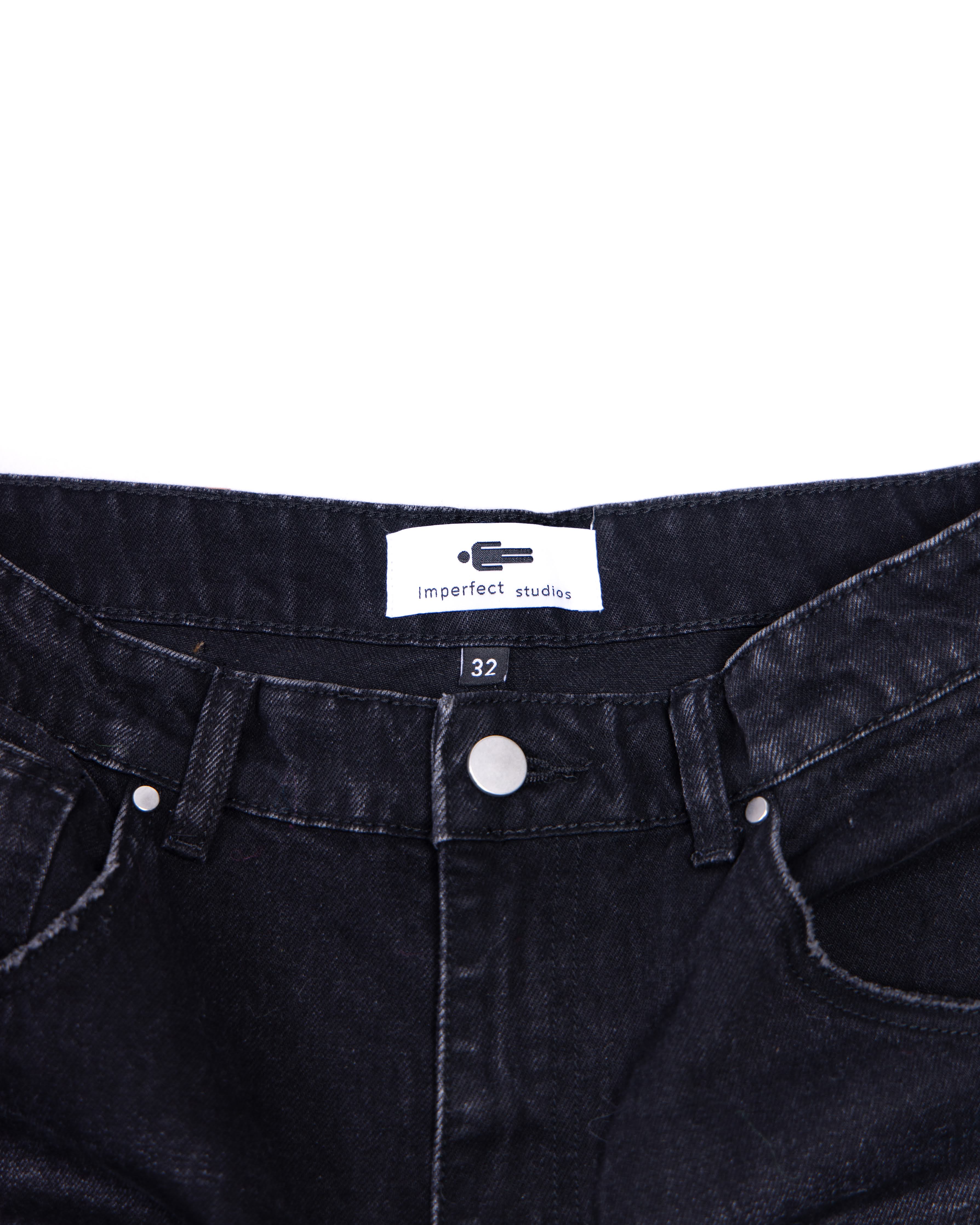 Close-up of black denim jeans with a brand label on a white background