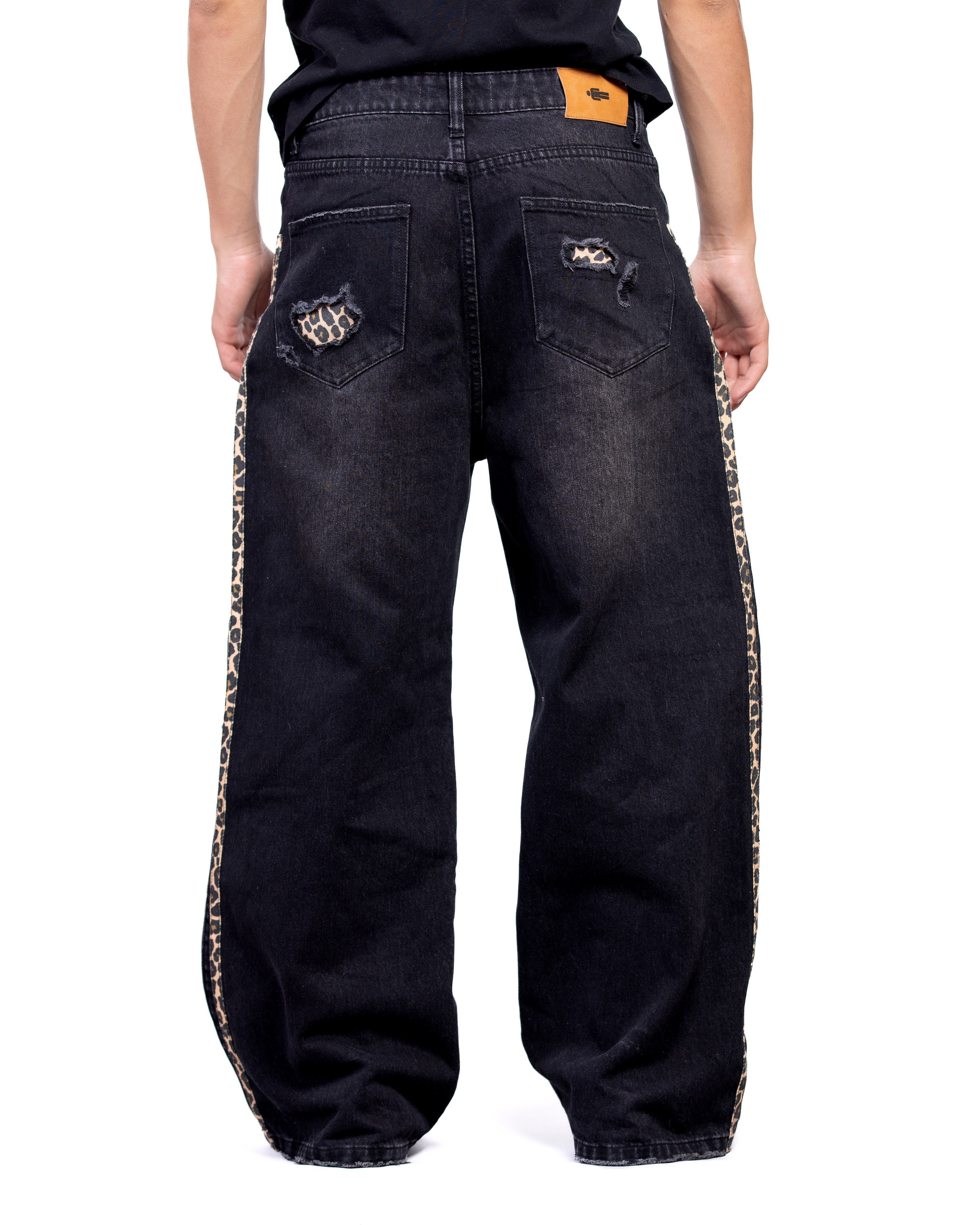 Black baggy jeans with decorative side panels on a white background